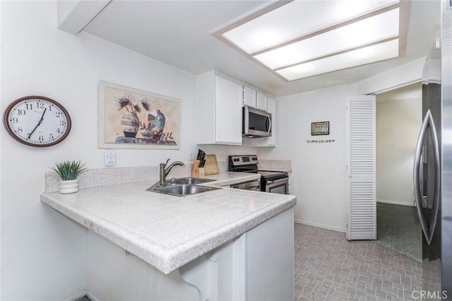 kitchen with white cabinets, sink, kitchen peninsula, and stainless steel appliances