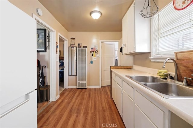 kitchen featuring light wood-type flooring, decorative light fixtures, white cabinetry, and sink