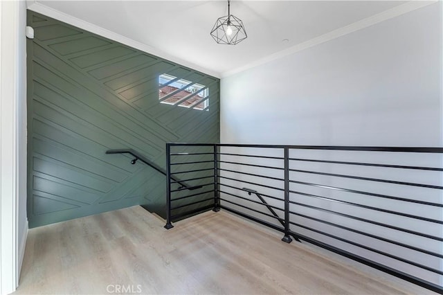 staircase with wooden walls, hardwood / wood-style flooring, and ornamental molding