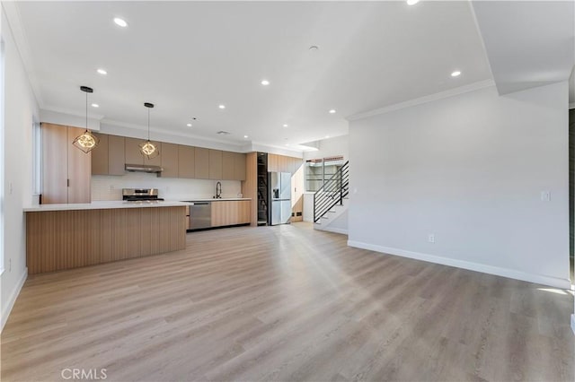 kitchen featuring light brown cabinets, hanging light fixtures, crown molding, appliances with stainless steel finishes, and light wood-type flooring