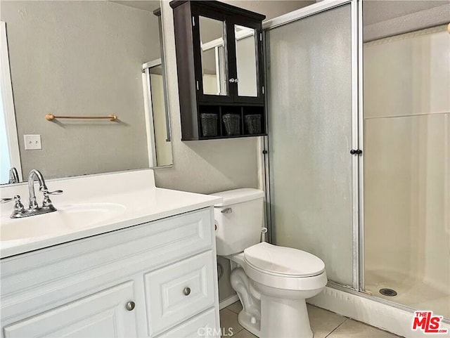 bathroom with vanity, tile patterned floors, toilet, and an enclosed shower