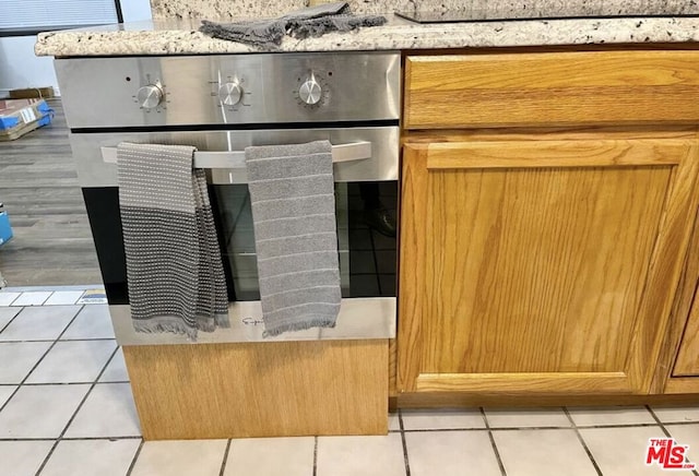 interior details featuring light tile patterned flooring and light stone counters