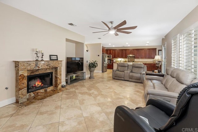 living room with ceiling fan, a premium fireplace, and light tile patterned floors