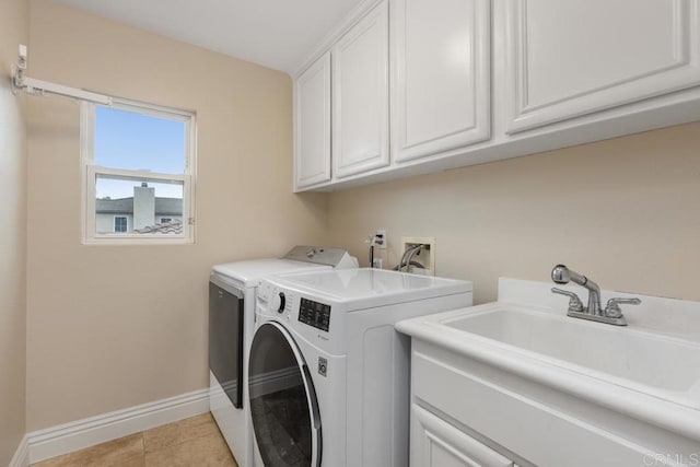 clothes washing area with sink, washer and dryer, light tile patterned flooring, and cabinets