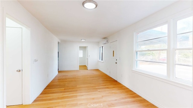 hallway featuring light hardwood / wood-style flooring and a wall unit AC