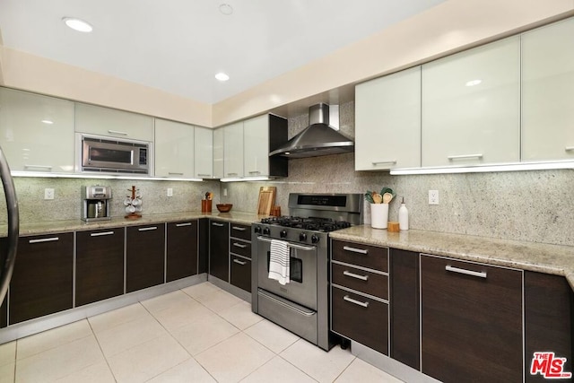 kitchen with white cabinetry, light tile patterned floors, tasteful backsplash, wall chimney range hood, and appliances with stainless steel finishes