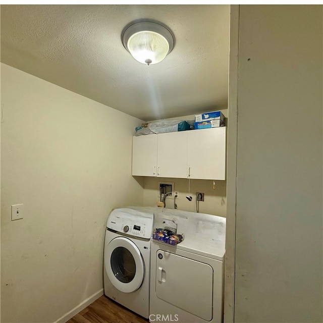 laundry area featuring cabinets, washing machine and clothes dryer, and dark hardwood / wood-style flooring