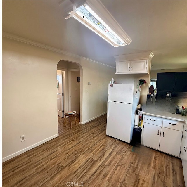 kitchen with decorative backsplash, white cabinets, light wood-type flooring, ornamental molding, and white refrigerator