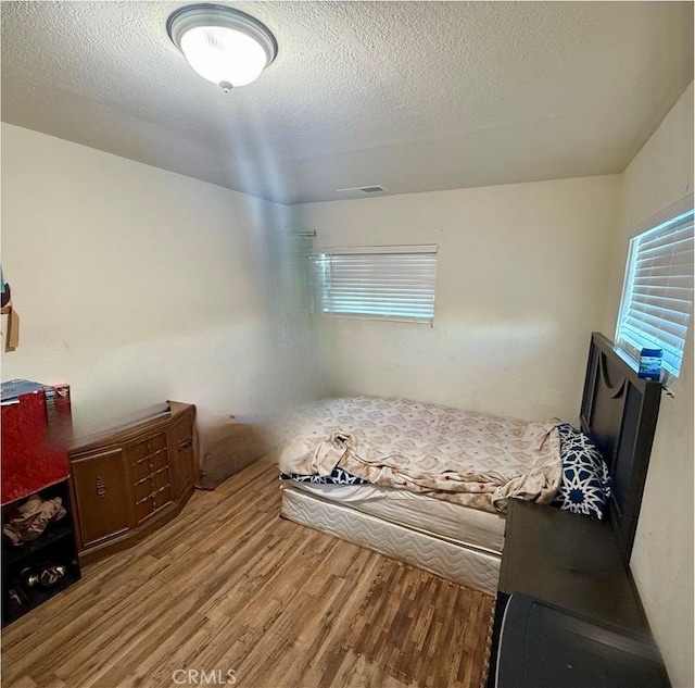 bedroom with light hardwood / wood-style floors and a textured ceiling