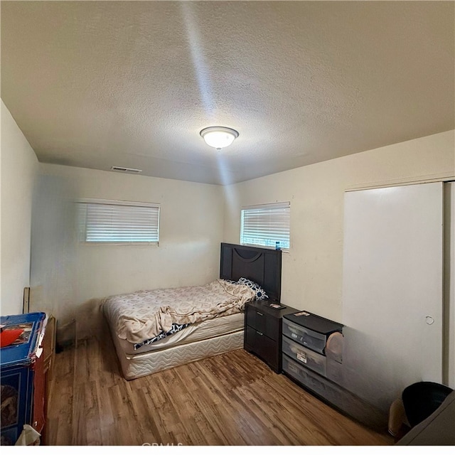 bedroom featuring hardwood / wood-style floors and a textured ceiling