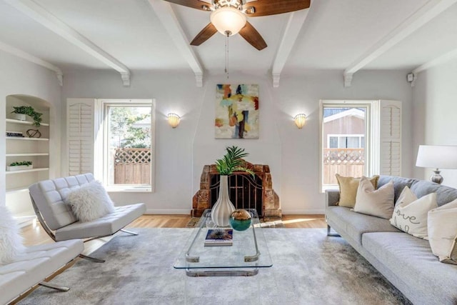 living room with ceiling fan, light hardwood / wood-style floors, built in shelves, and beam ceiling