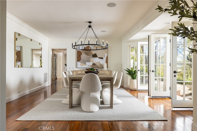 dining space with hardwood / wood-style flooring, ornamental molding, and an inviting chandelier