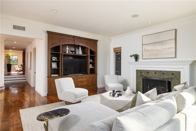 living room with ornamental molding, a tiled fireplace, and dark hardwood / wood-style flooring