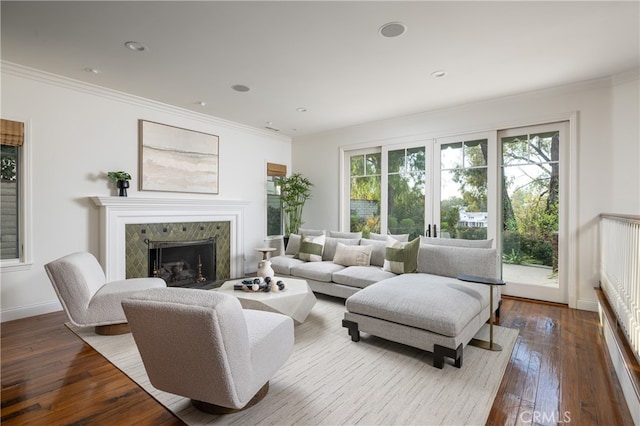 living room featuring crown molding, hardwood / wood-style flooring, and a tile fireplace