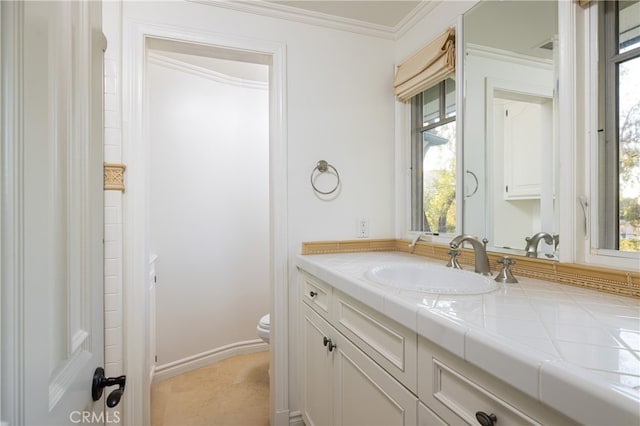 bathroom with toilet, ornamental molding, a healthy amount of sunlight, and vanity