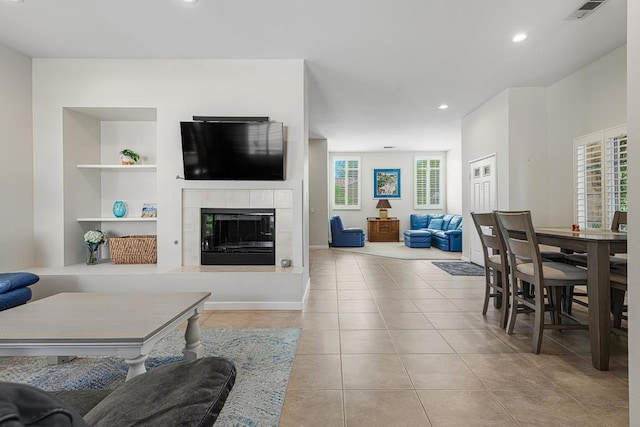 tiled living room featuring a tile fireplace and built in shelves