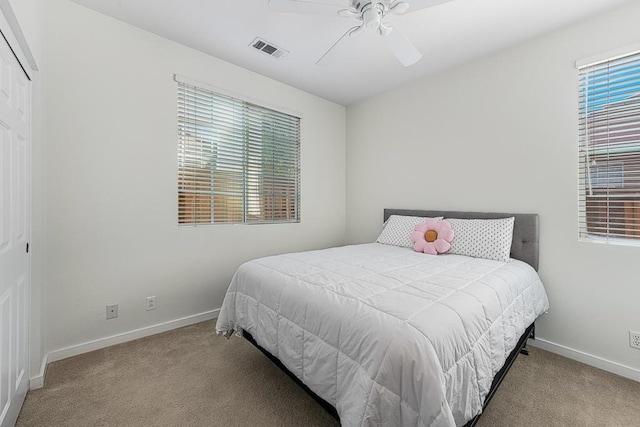 bedroom with ceiling fan, light colored carpet, and a closet