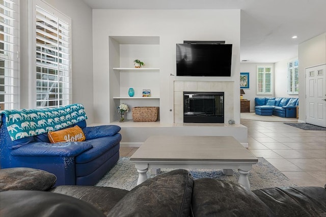 living room with tile patterned flooring, built in features, and a tiled fireplace