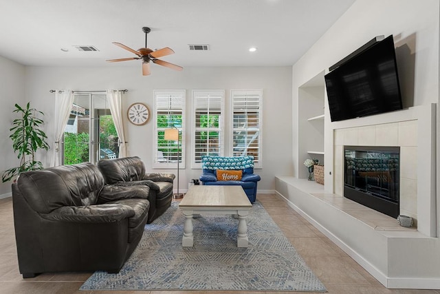 tiled living room with ceiling fan and a tiled fireplace