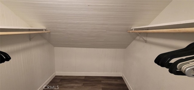 walk in closet with dark wood-type flooring and vaulted ceiling