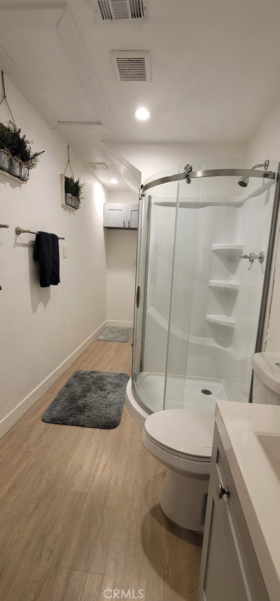 bathroom with vanity, toilet, wood-type flooring, and a shower with shower door