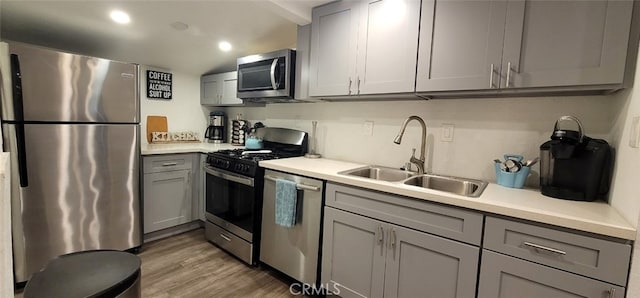 kitchen with gray cabinetry, appliances with stainless steel finishes, sink, and light wood-type flooring