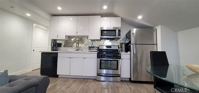 kitchen with tasteful backsplash, appliances with stainless steel finishes, light wood-type flooring, lofted ceiling, and white cabinets