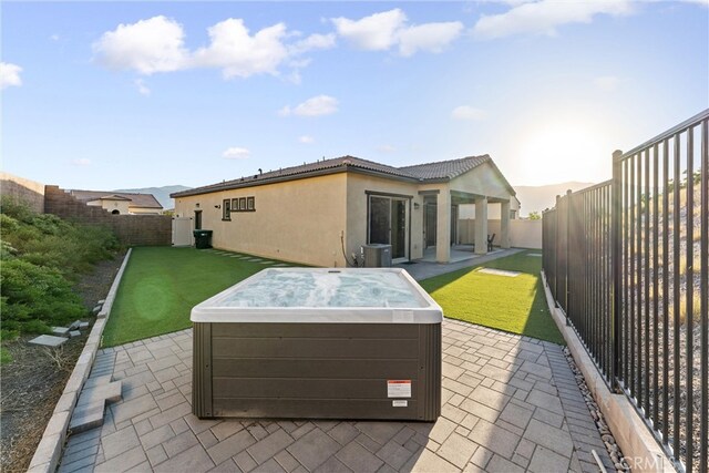 rear view of property featuring a patio and a hot tub