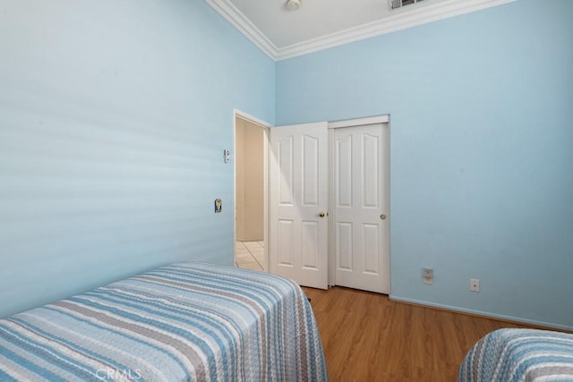 bedroom with crown molding, a closet, a high ceiling, and light wood-type flooring