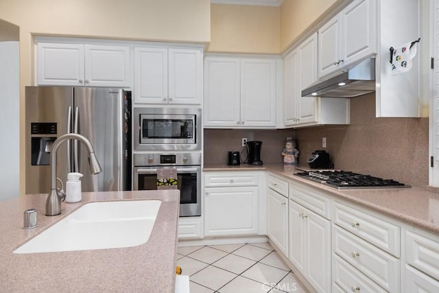 kitchen featuring sink, decorative backsplash, light tile patterned floors, appliances with stainless steel finishes, and white cabinetry