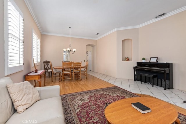 living room with light hardwood / wood-style floors, ornamental molding, and an inviting chandelier