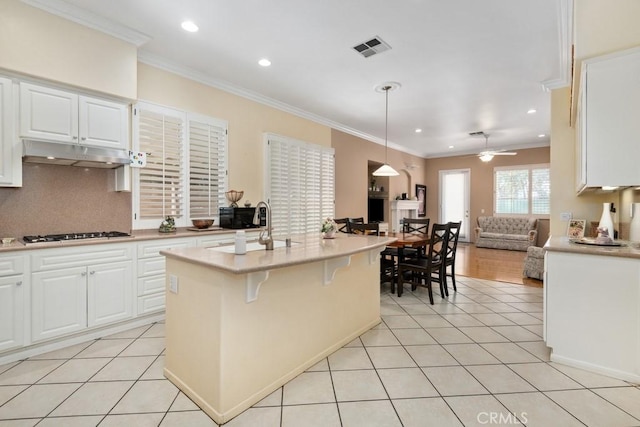 kitchen with a kitchen breakfast bar, a kitchen island with sink, decorative light fixtures, white cabinetry, and stainless steel gas stovetop