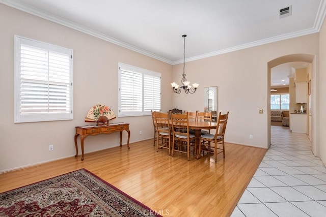 dining space featuring light hardwood / wood-style flooring, a wealth of natural light, ornamental molding, and a notable chandelier