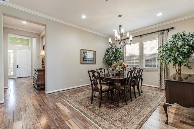 dining area featuring an inviting chandelier, ornamental molding, and hardwood / wood-style flooring