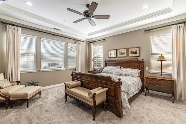 carpeted bedroom with a tray ceiling, ceiling fan, and ornamental molding