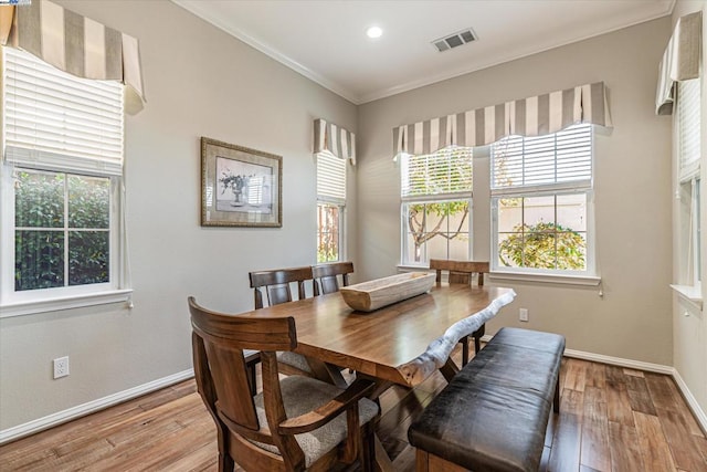 dining area with crown molding and light hardwood / wood-style flooring