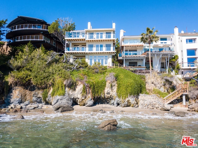 back of property with a water view and a pergola