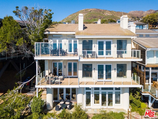 back of house featuring an outdoor living space, a patio area, a mountain view, french doors, and a balcony