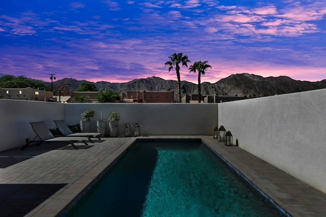 pool at dusk with a patio and a mountain view