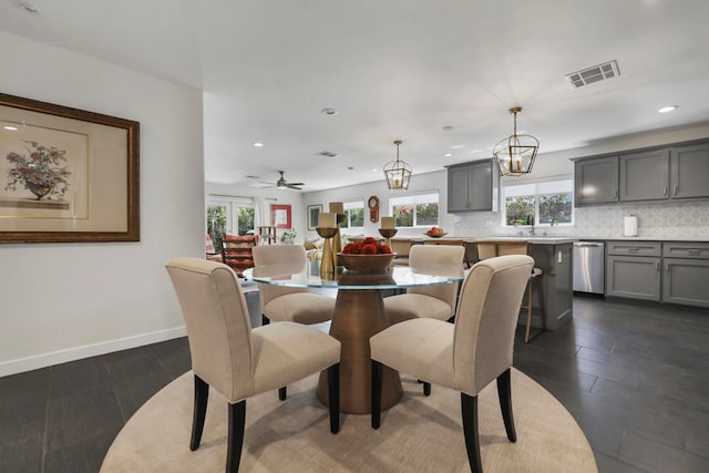 dining area featuring a wealth of natural light, ceiling fan with notable chandelier, and dark hardwood / wood-style flooring