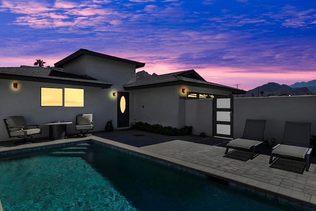 back house at dusk with a patio and a fenced in pool