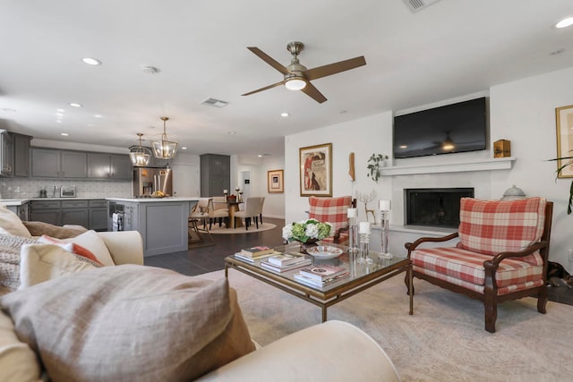 living room featuring ceiling fan with notable chandelier and light wood-type flooring