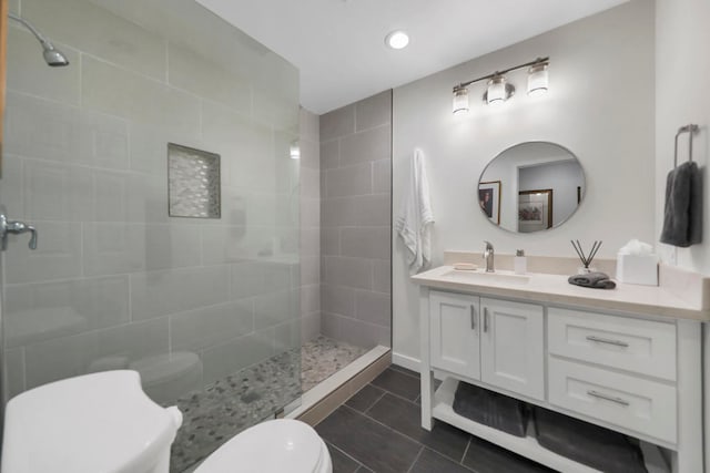 bathroom with toilet, vanity, tile patterned floors, and tiled shower