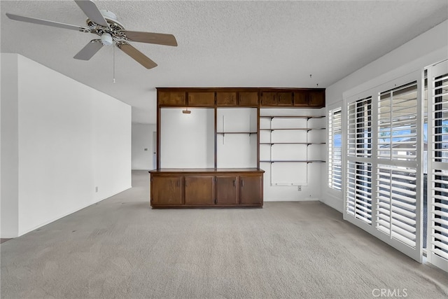 interior space with ceiling fan, a textured ceiling, and light colored carpet