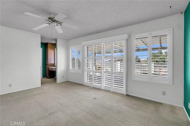 unfurnished room with a textured ceiling, light colored carpet, and ceiling fan