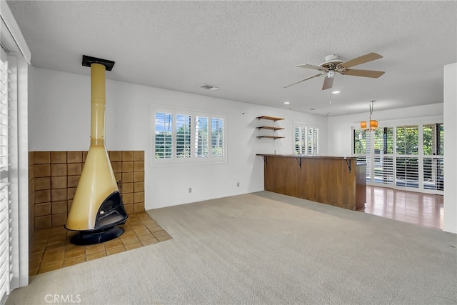 unfurnished living room with tile walls, light carpet, a textured ceiling, and ceiling fan