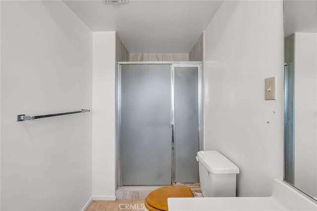 bathroom featuring toilet and a shower with shower door