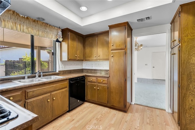 kitchen featuring backsplash, a tray ceiling, dishwasher, light hardwood / wood-style floors, and sink