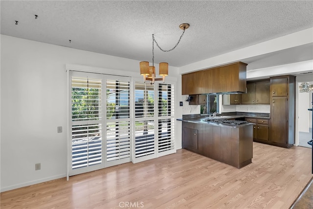 kitchen featuring light hardwood / wood-style flooring, a textured ceiling, a chandelier, and pendant lighting