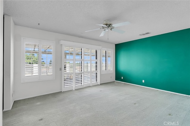 carpeted spare room with a textured ceiling and ceiling fan